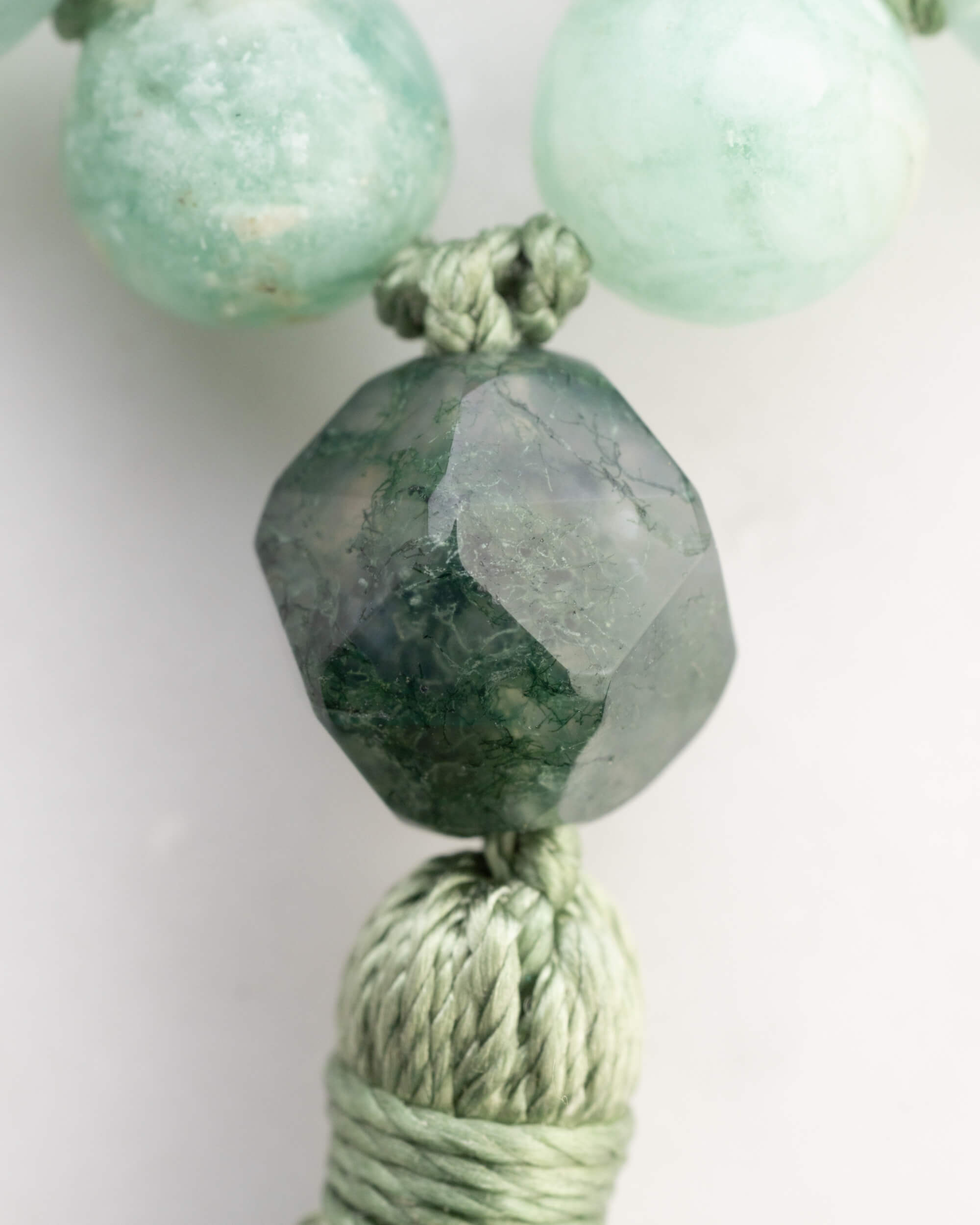 Detalle macro de la cuenta facetada de Ágata Musgosa y la borla verde del Japa Mala Corazon