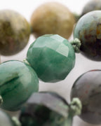 Detalle macro de una cuenta facetada verde oliva con manchas oscuras