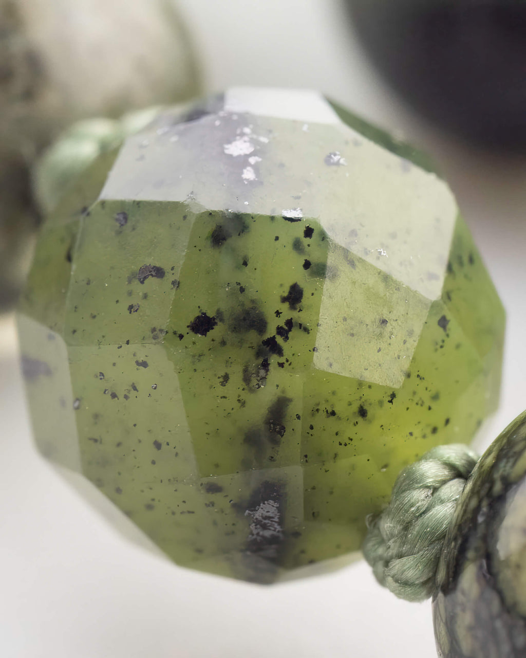Detalle macro de una cuenta facetada translucida verde de gran tamano