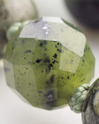 Detalle macro de una cuenta facetada translucida verde de gran tamano