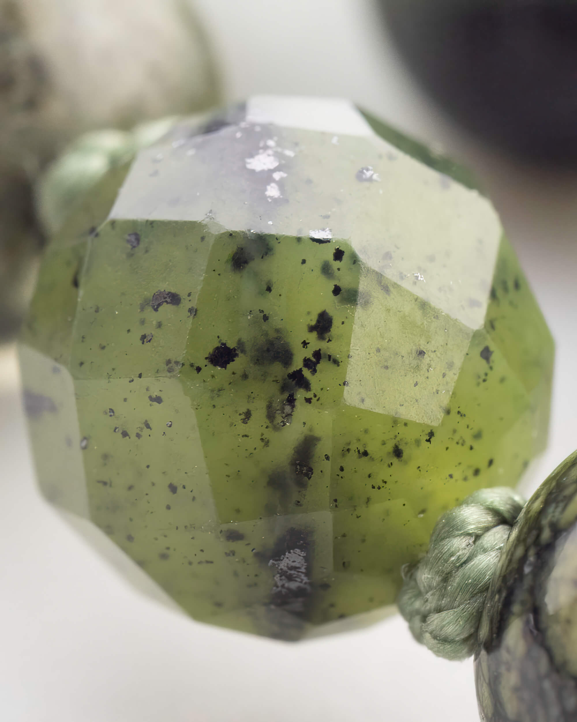 Detalle macro de una cuenta facetada translucida verde de gran tamano