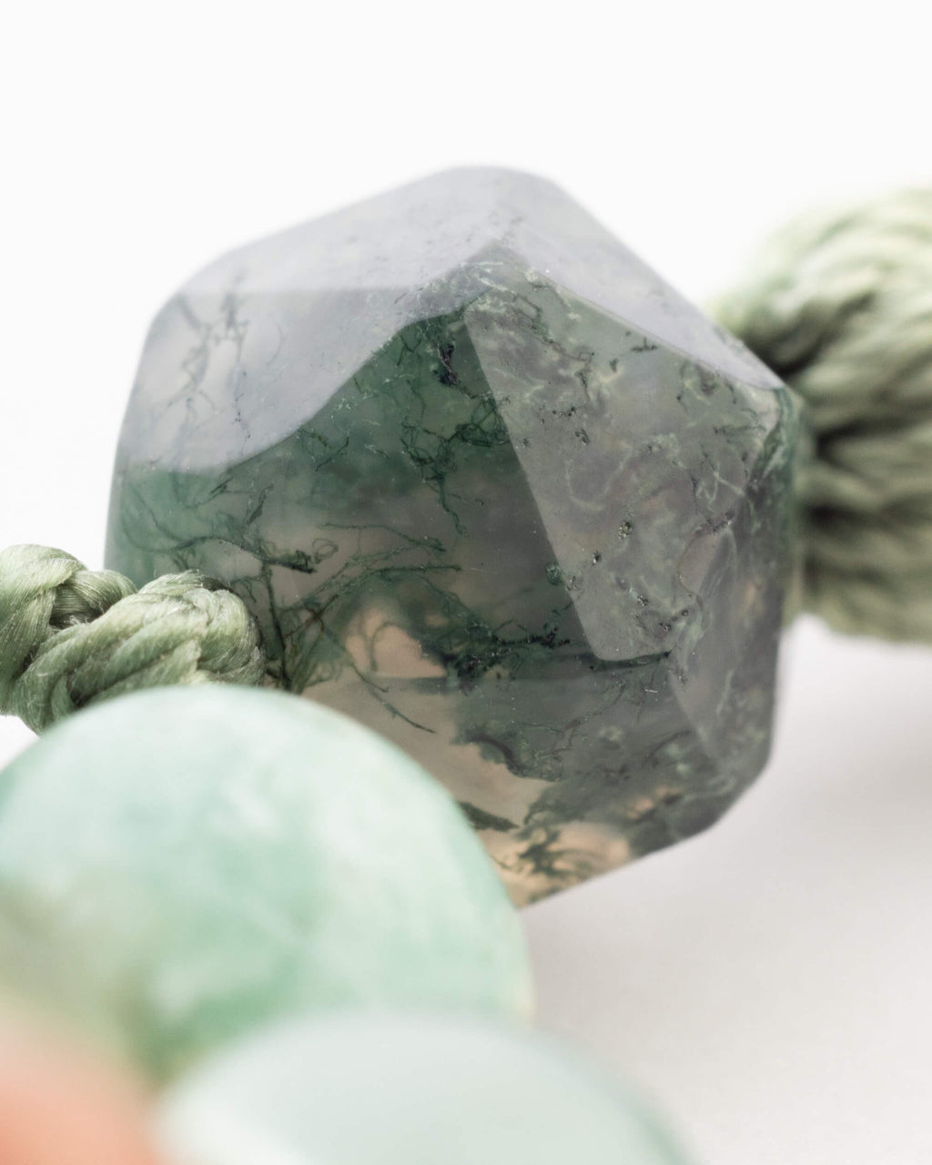 Detalle macro de una cuenta angular verde oscura con vetas negras del Japa Mala Corazon