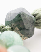 Detalle macro de una cuenta angular verde oscura con vetas negras del Japa Mala Corazon