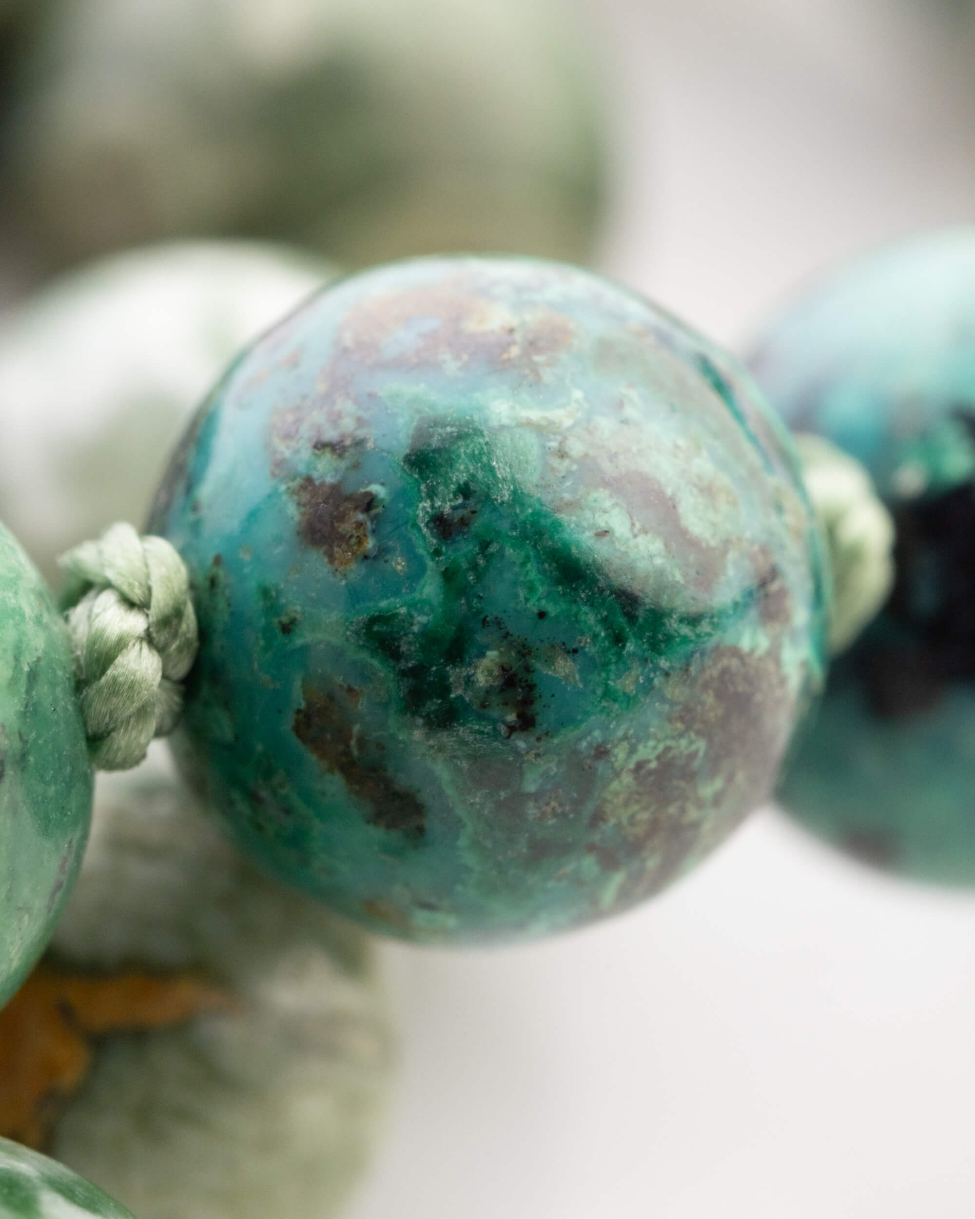 Detalle macro de una cuenta veteada verde y blanca junto a otras cuentas moteadas