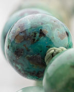 Detalle macro de una cuenta de Turquesa Africana en tonos verde azulado con manchas oscuras