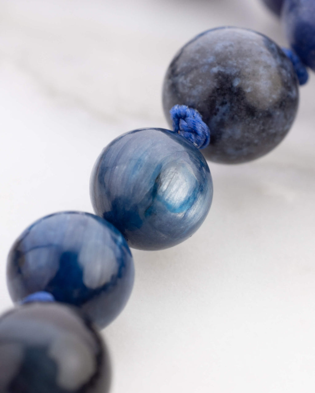 Detalle macro de cuentas redondas azules con brillo aperlado y vetas grisaceas del Japa Mala Universo