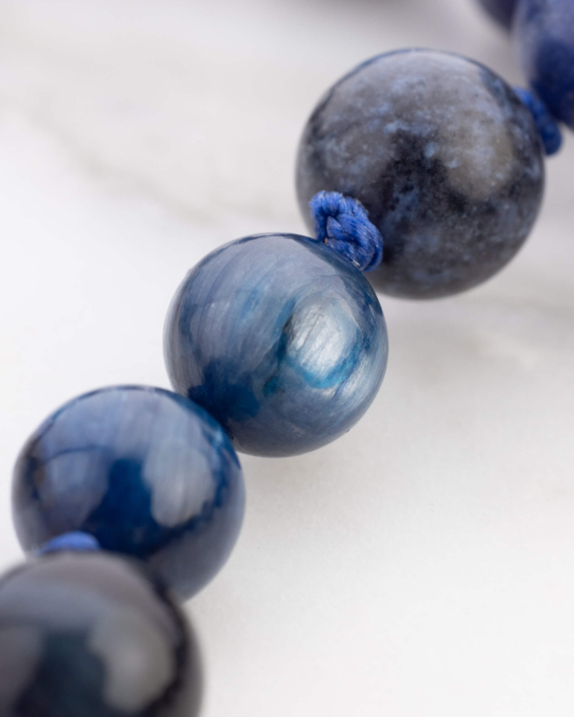 Detalle macro de cuentas redondas azules con brillo aperlado y vetas grisaceas del Japa Mala Universo