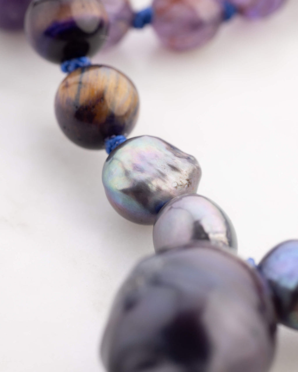 Detalle macro de una perla barroca junto a Ojo de Tigre del Japa Mala Universo
