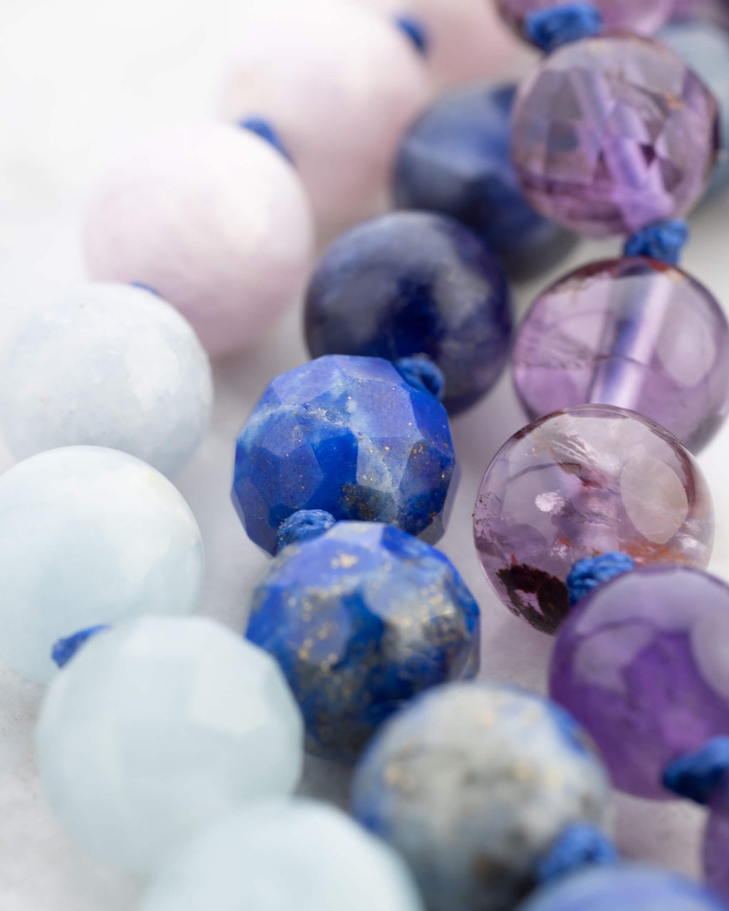 Detalle macro de cuentas azul marino facetadas junto a cuentas rosas y lilas