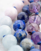 Detalle macro de cuentas azul marino facetadas junto a cuentas rosas y lilas