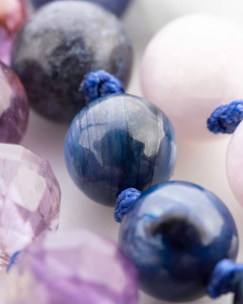 Detalle macro de una cuenta azul facetada entre cuentas oscuras y una cuenta rosa clara