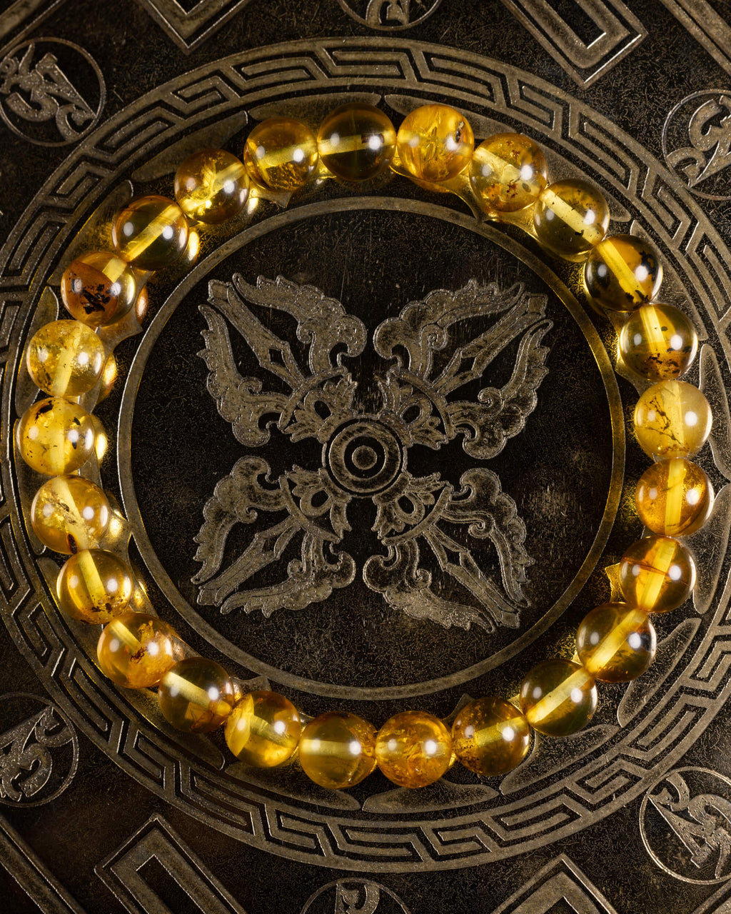 Pulsera de Ámbar en círculo sobre plato metálico grabado con motivo oriental