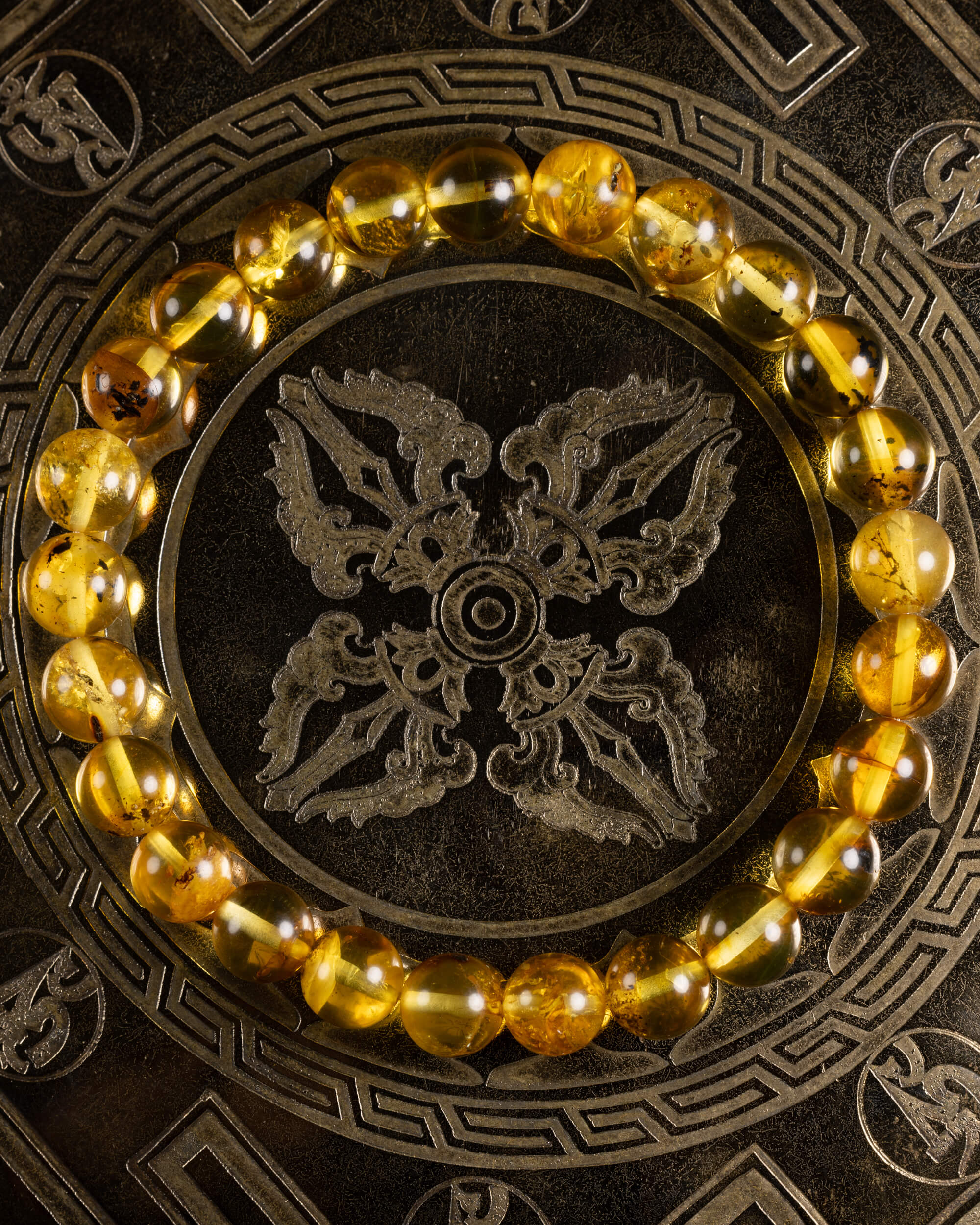 Pulsera de Ámbar en círculo sobre plato metálico grabado con motivo oriental