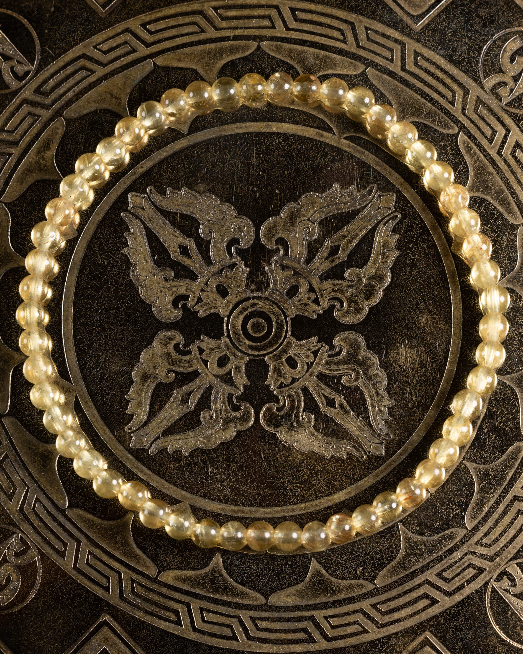 Pulsera de Cuarzo Rutilado de 4 mm, pieza completa sobre disco decorativo oscuro