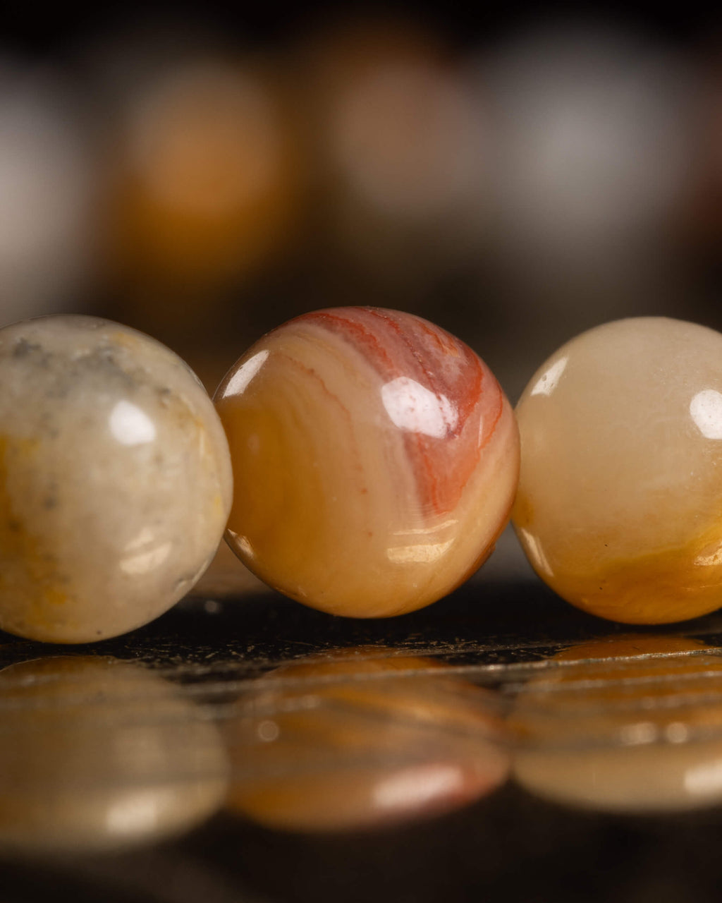 Detalle macro de tres cuentas de Ágata Mexicana con bandeado naranja y blanco