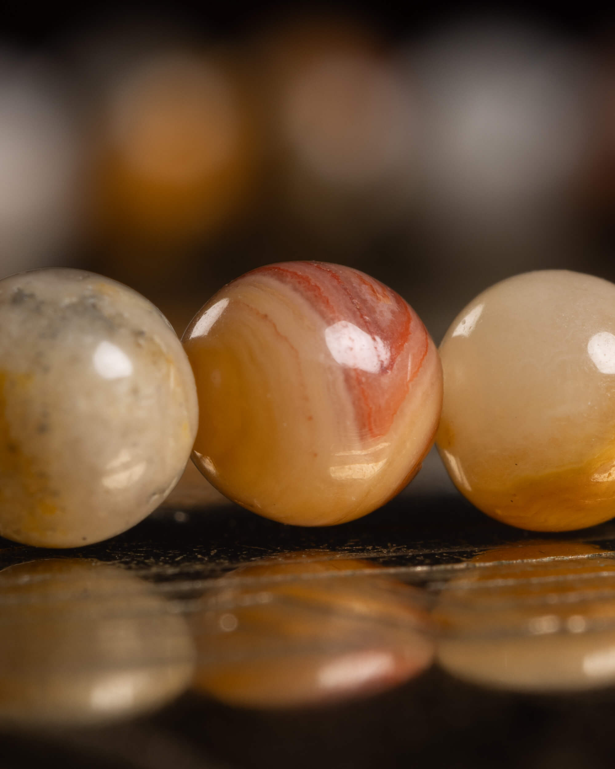 Detalle macro de tres cuentas de Ágata Mexicana con bandeado naranja y blanco