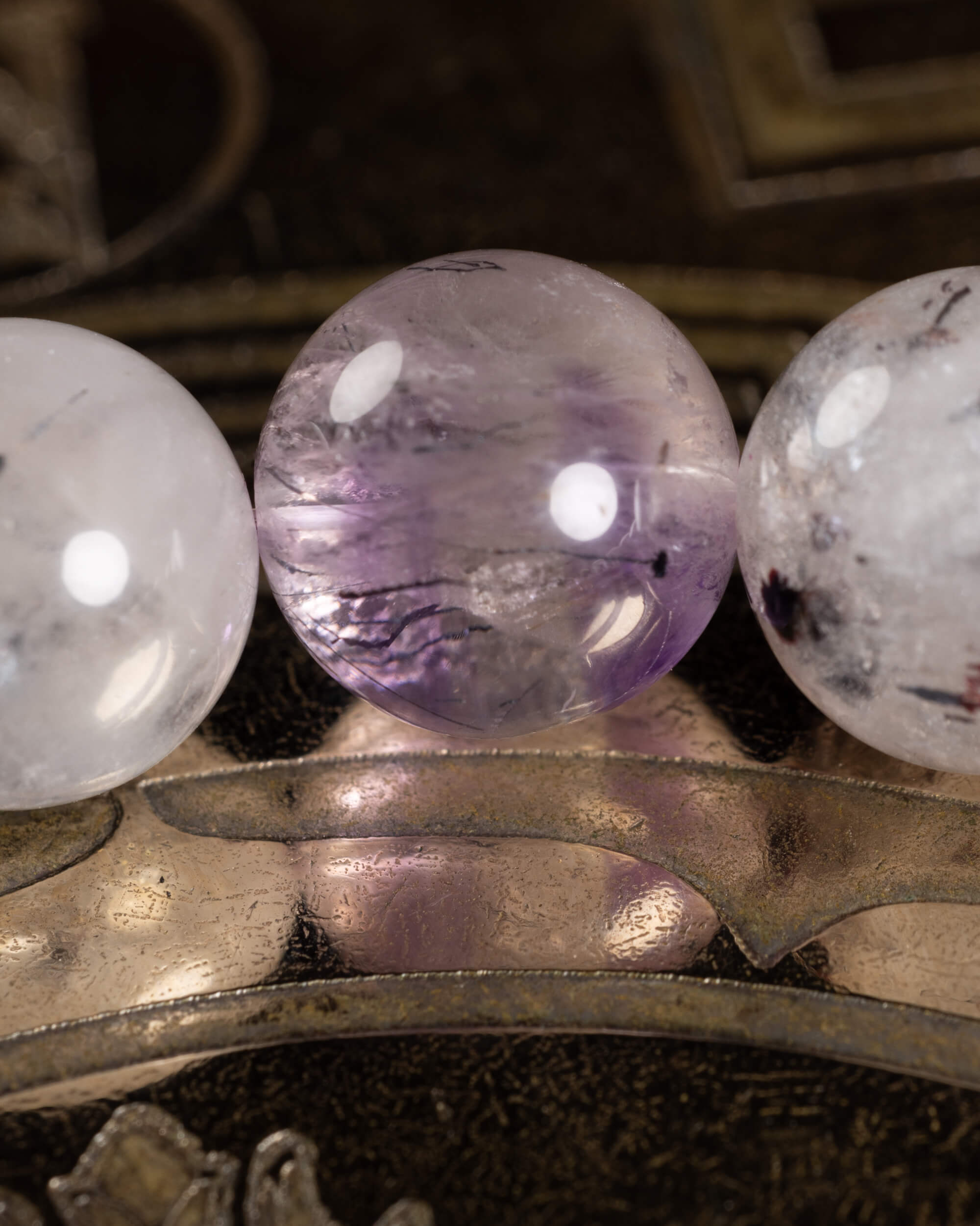 Detalle macro de tres cuentas de Super 7, una en tono lila con vetas oscuras