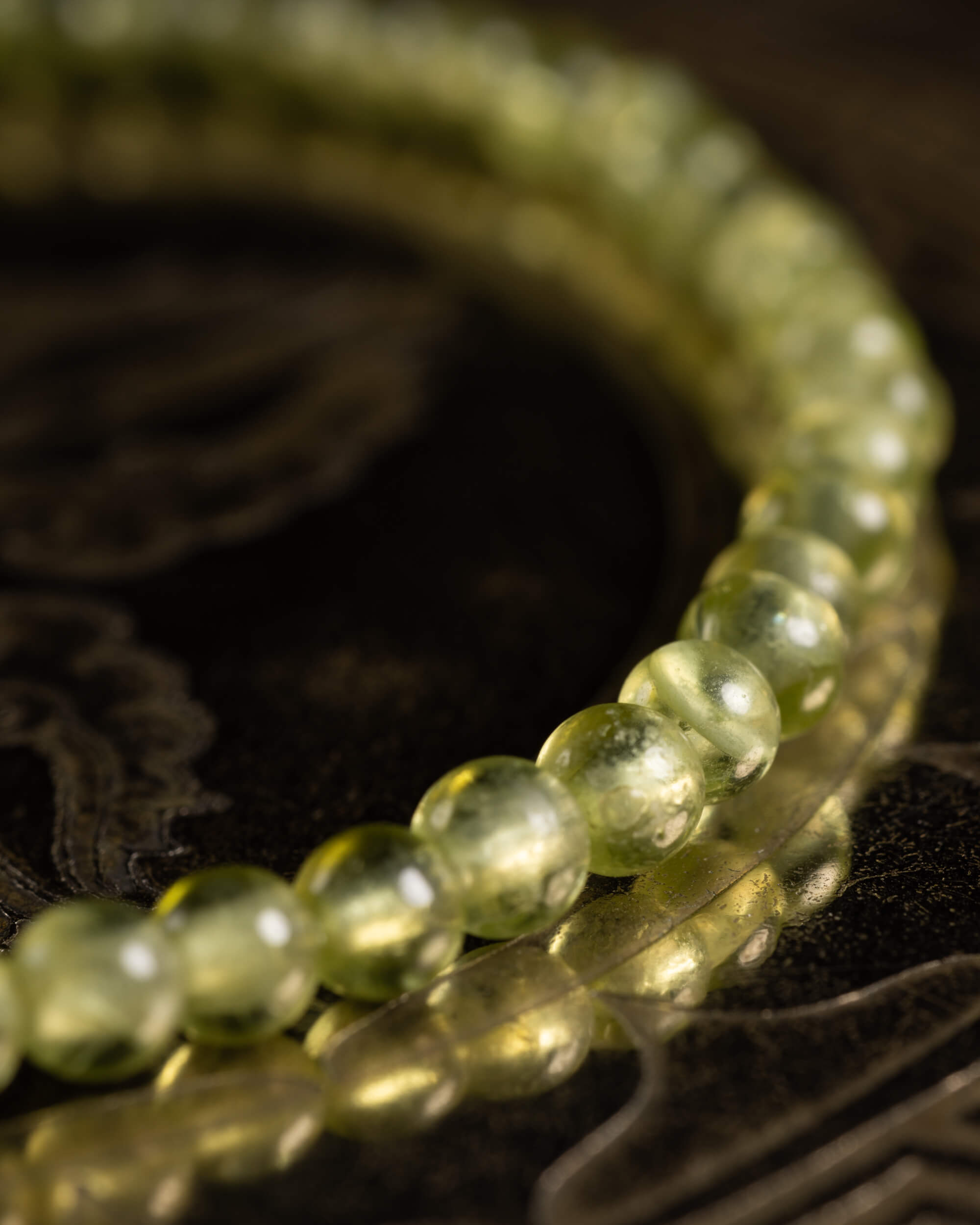 Pulsera de Peridoto vista en angulo sobre soporte metálico grabado