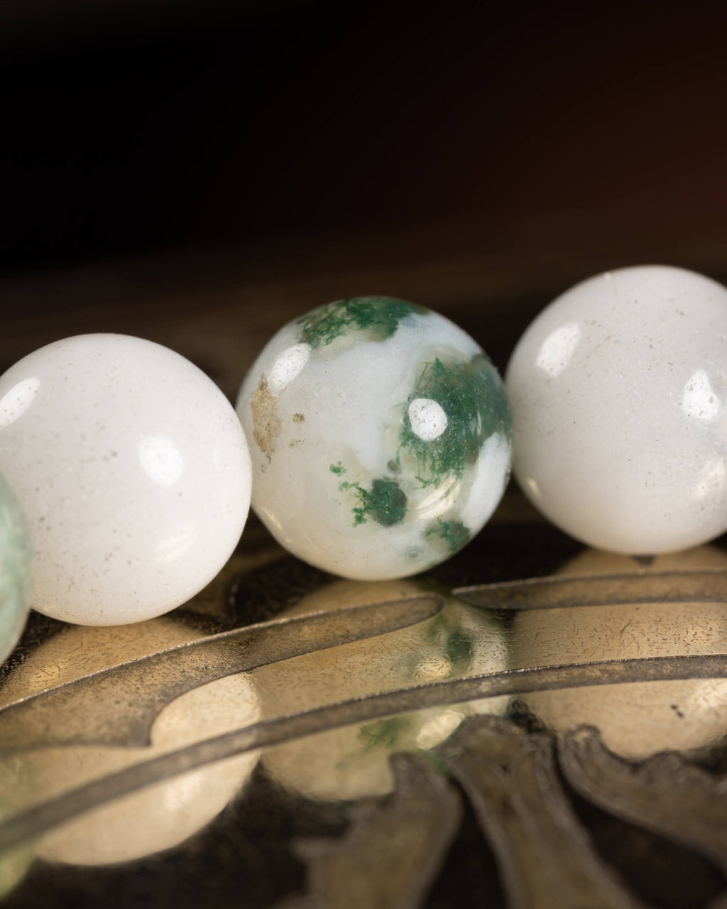 Detalle macro de tres cuentas de Ágata Arbol blancas, una con manchas verdes