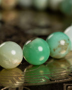 Detalle macro de tres cuentas de Crisoprasa verde y crema sobre disco grabado