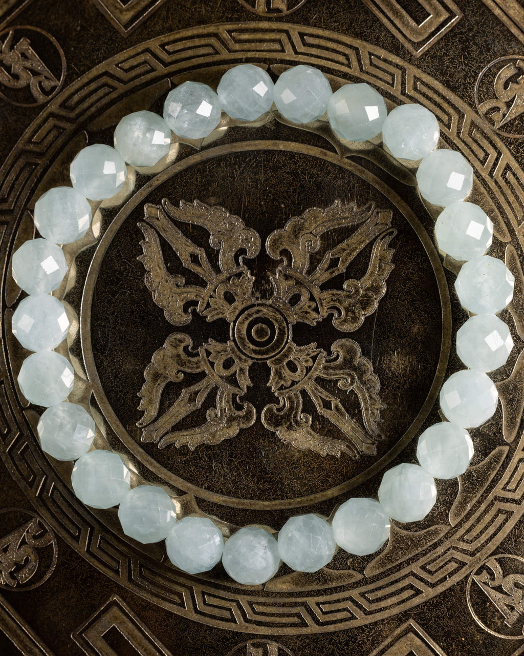 Pulsera de Aguamarina facetada, pieza completa en círculo sobre placa metálica grabada