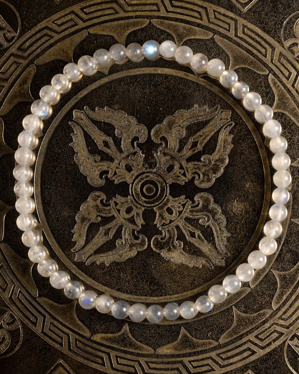 Pulsera de Labradorita, pieza completa en círculo sobre bandeja tallada de bronce
