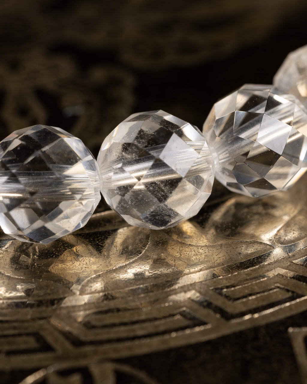 Detalle macro de tres cuentas facetadas de Cuarzo Transparente con destellos de luz