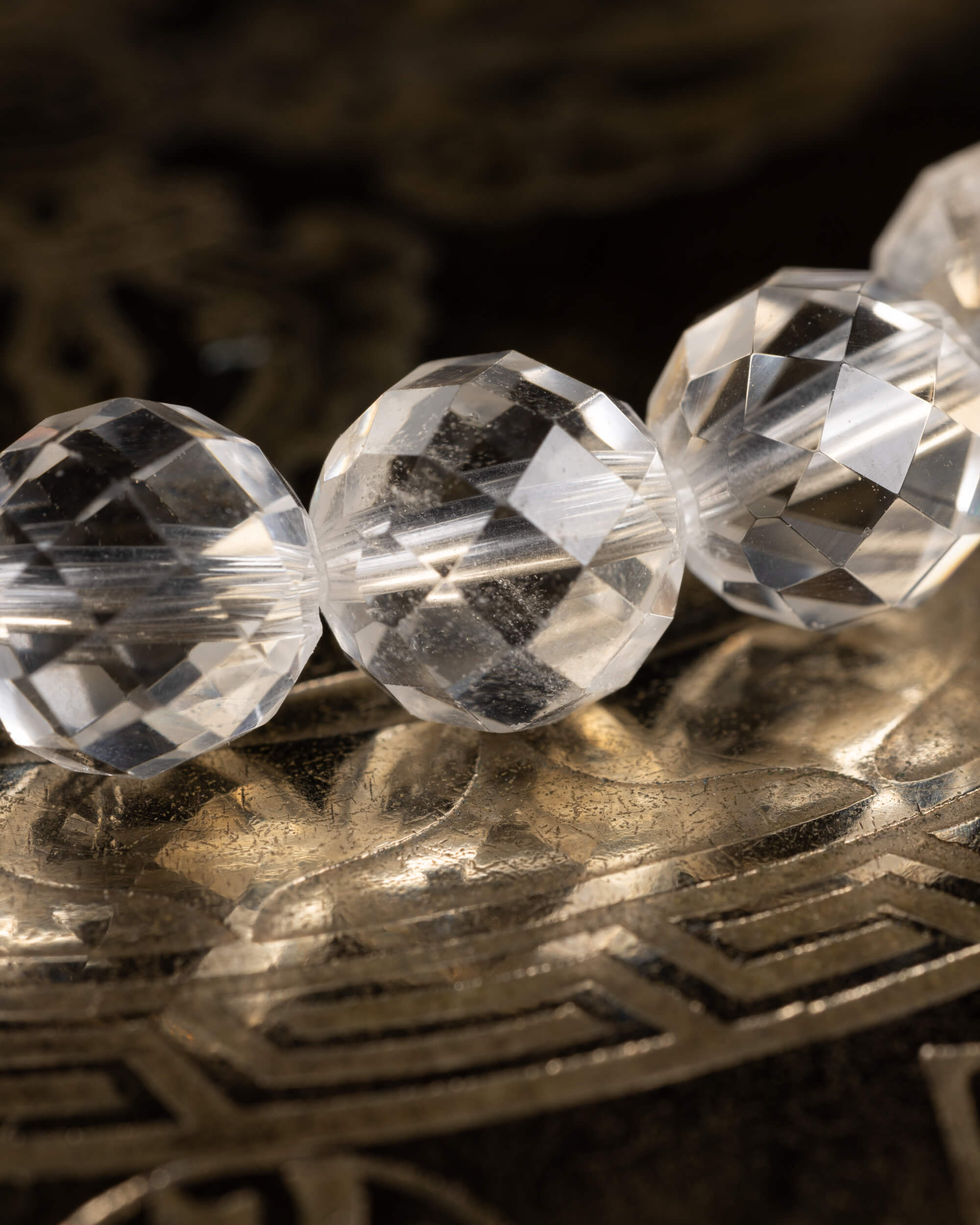 Detalle macro de tres cuentas facetadas de Cuarzo Transparente con destellos de luz