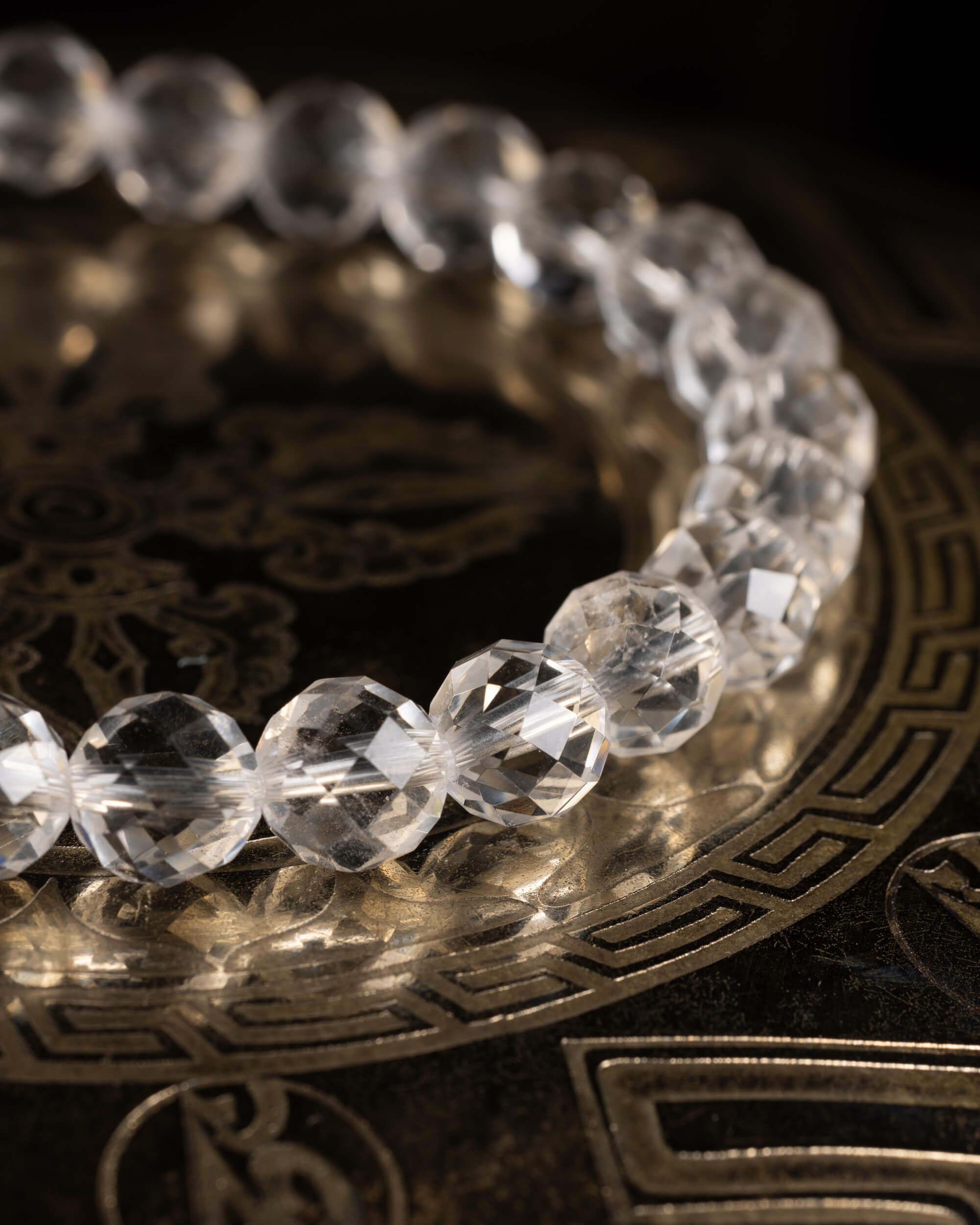 Pulsera de Cuarzo Transparente facetada, vista en perspectiva sobre soporte con grabado circular