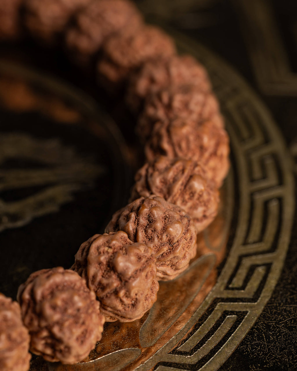 Detalle macro de las semillas de Rudraksha con relieve marcado sobre placa metálica