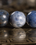 Detalle macro de tres cuentas de Dumortierita con moteado azul, gris y blanco