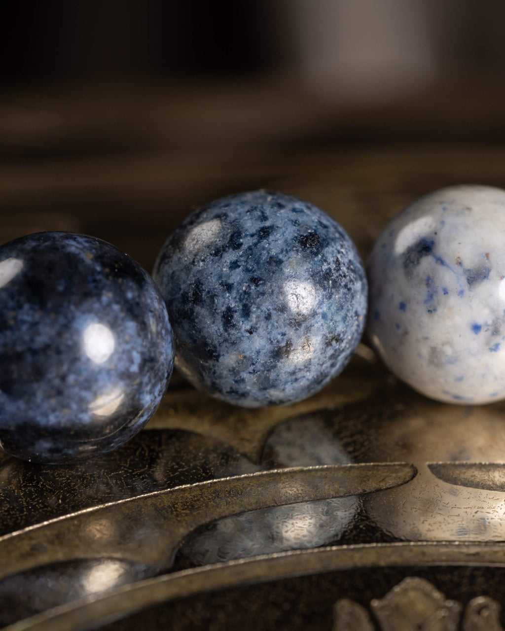 Detalle macro de tres cuentas de Dumortierita en tonos azul oscuro y gris