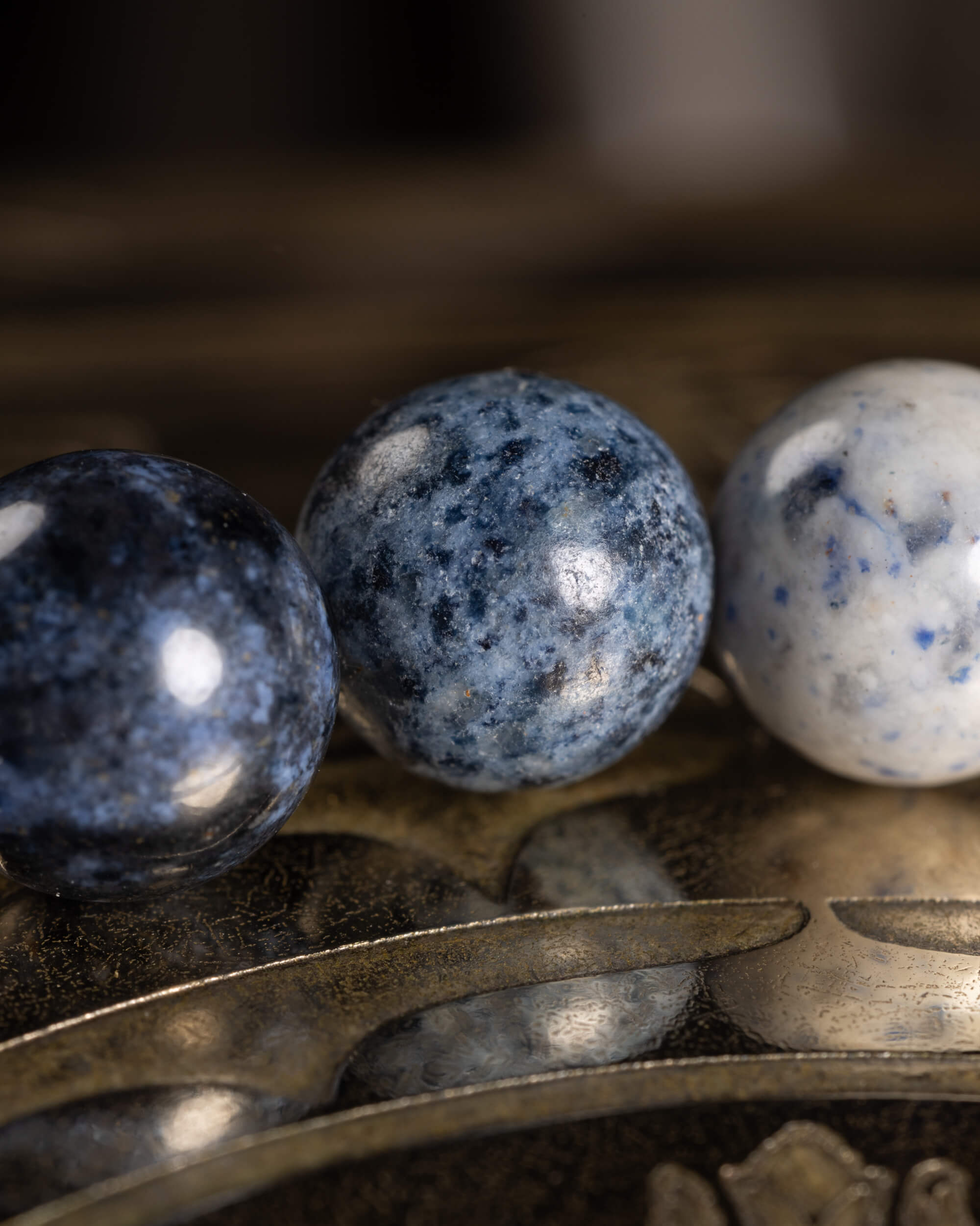 Detalle macro de tres cuentas de Dumortierita en tonos azul oscuro y gris