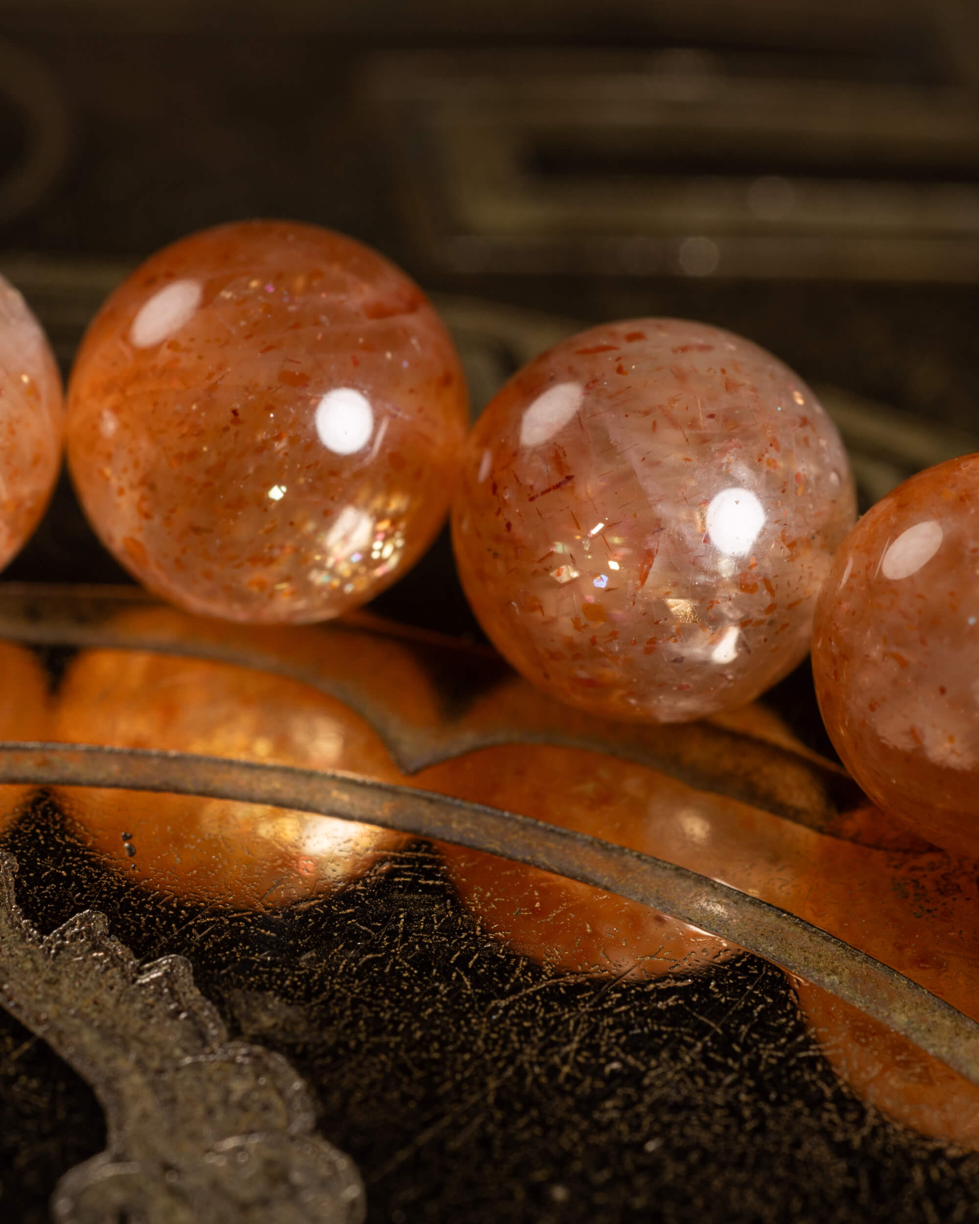 Detalle macro de tres cuentas de Piedra Sol Roja con destellos dorados