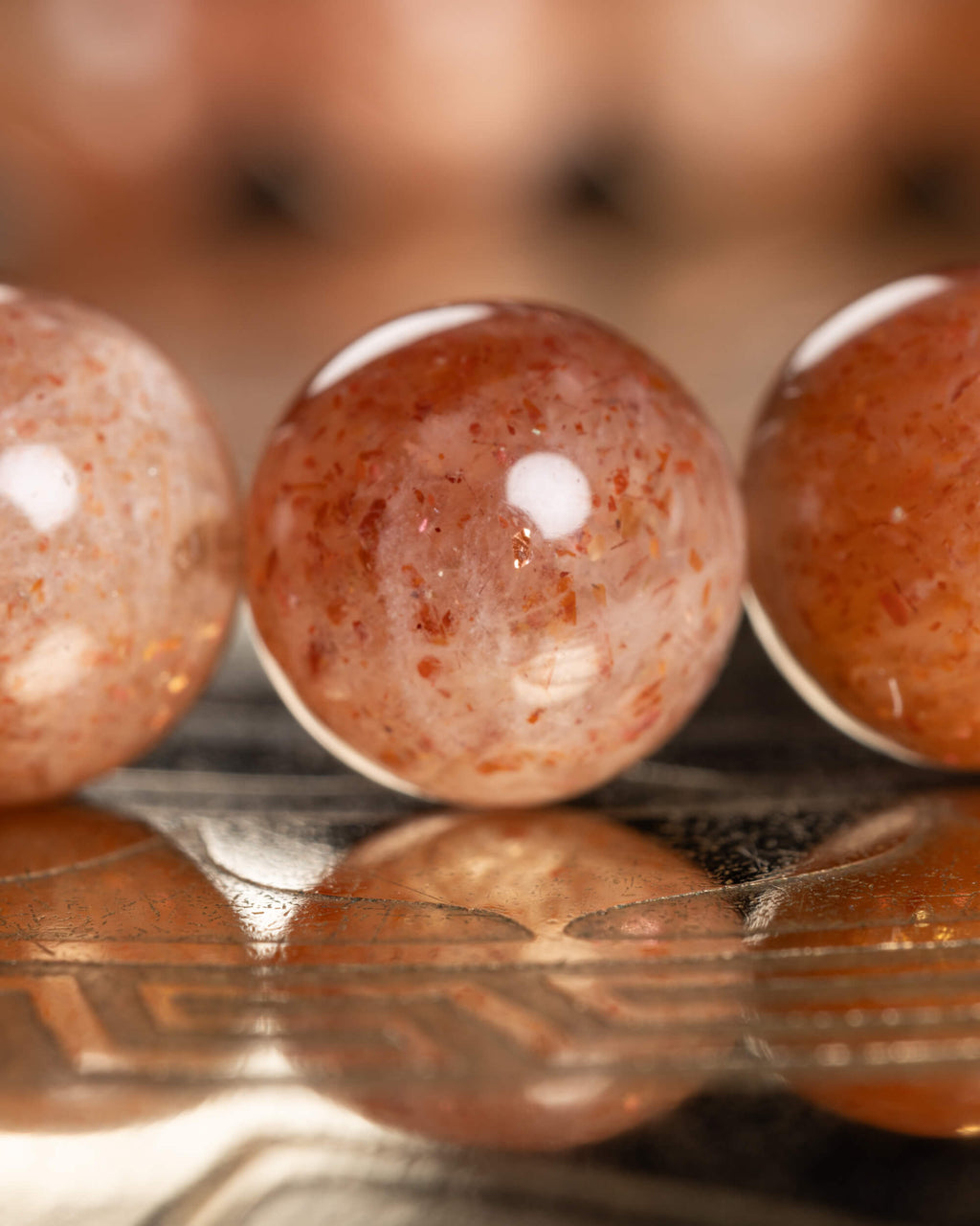 Detalle macro de tres cuentas de Piedra Sol Roja con destellos internos visibles
