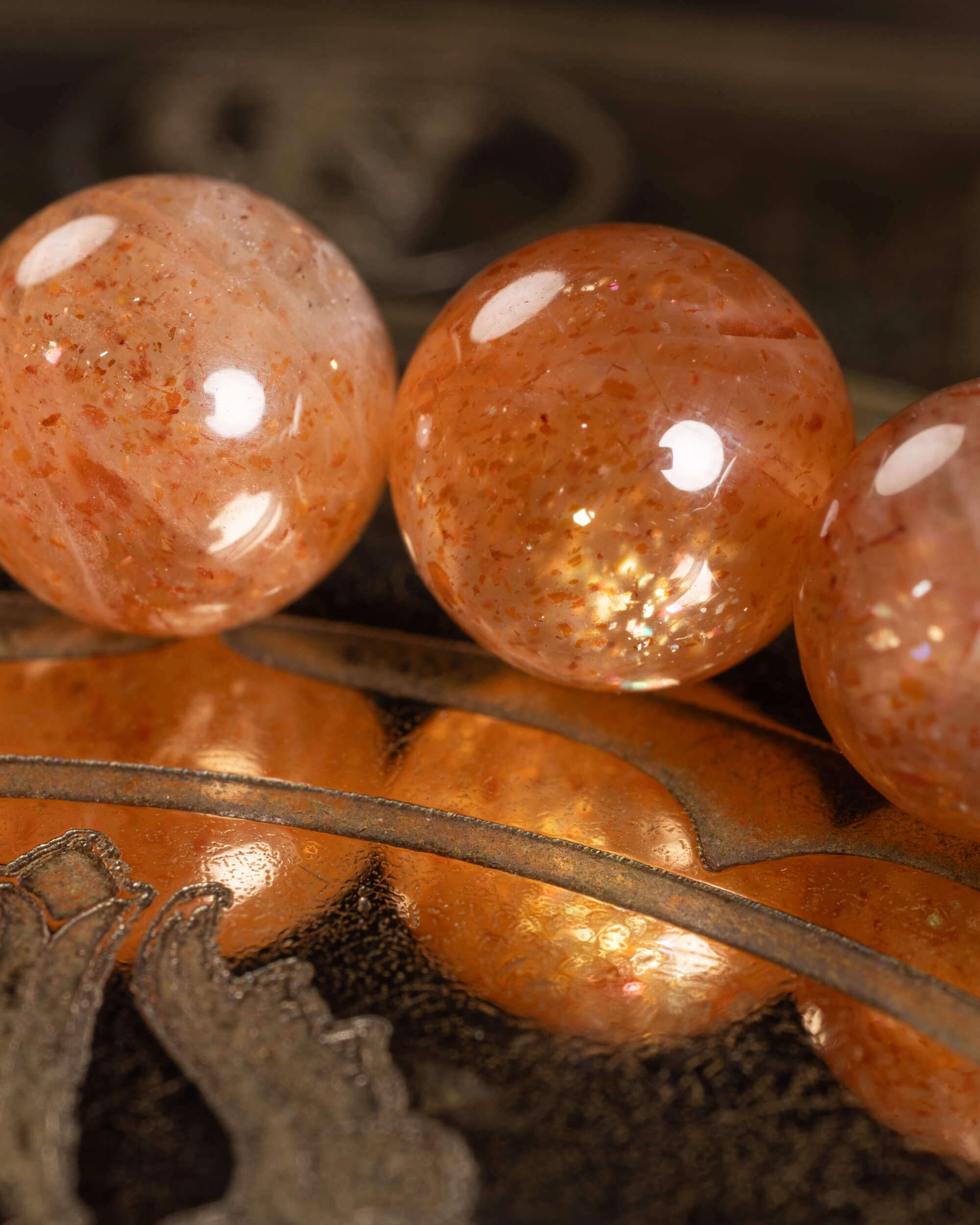 Detalle macro de las cuentas de Piedra Sol Roja con destellos dorados internos