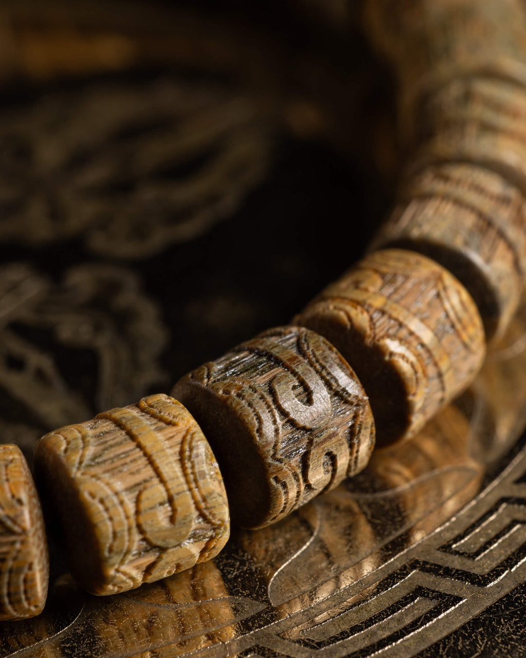 Detalle macro de las cuentas talladas de Madera de Sándalo sobre soporte oscuro