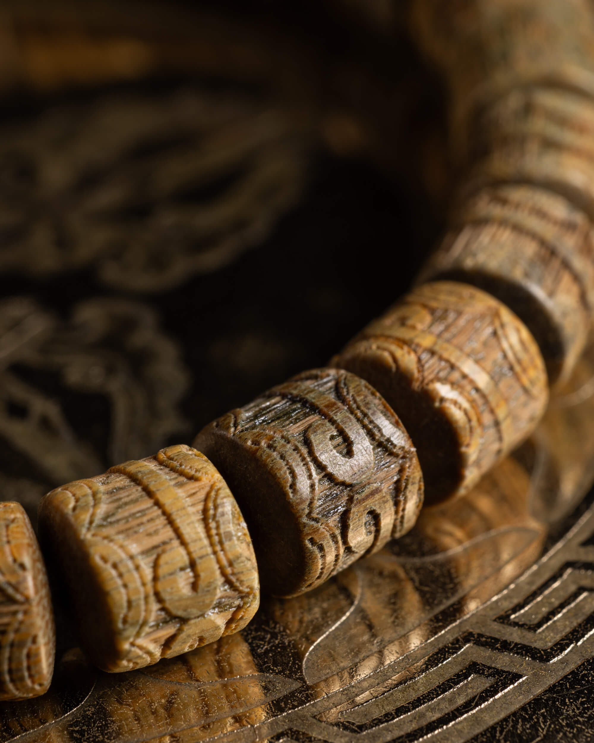 Detalle macro de las cuentas talladas de Madera de Sándalo sobre soporte oscuro