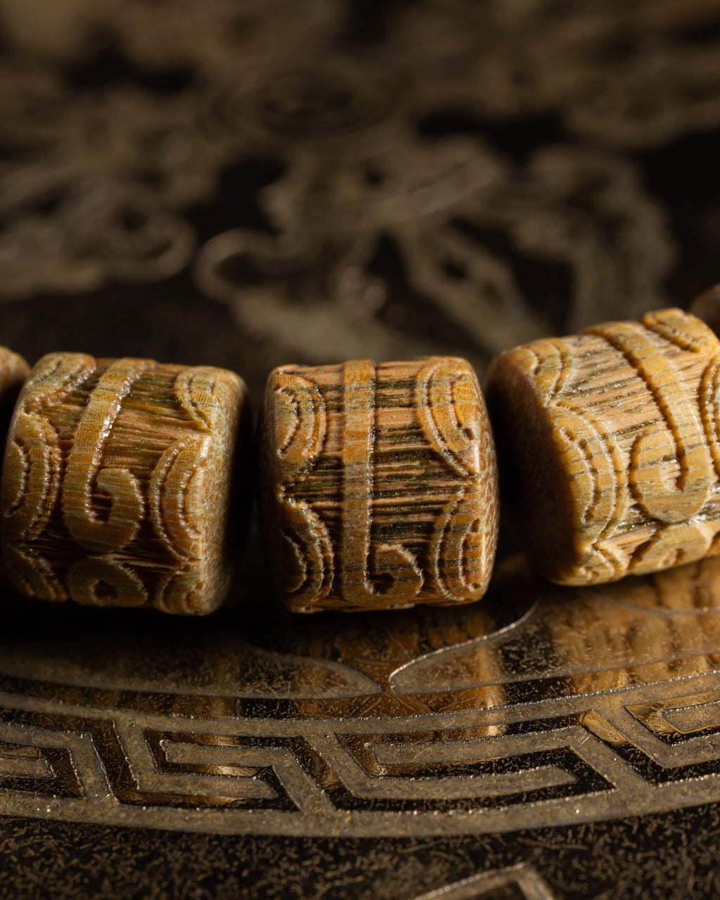 Detalle macro de tres cuentas cilíndricas de Madera de Sándalo con talla ornamental