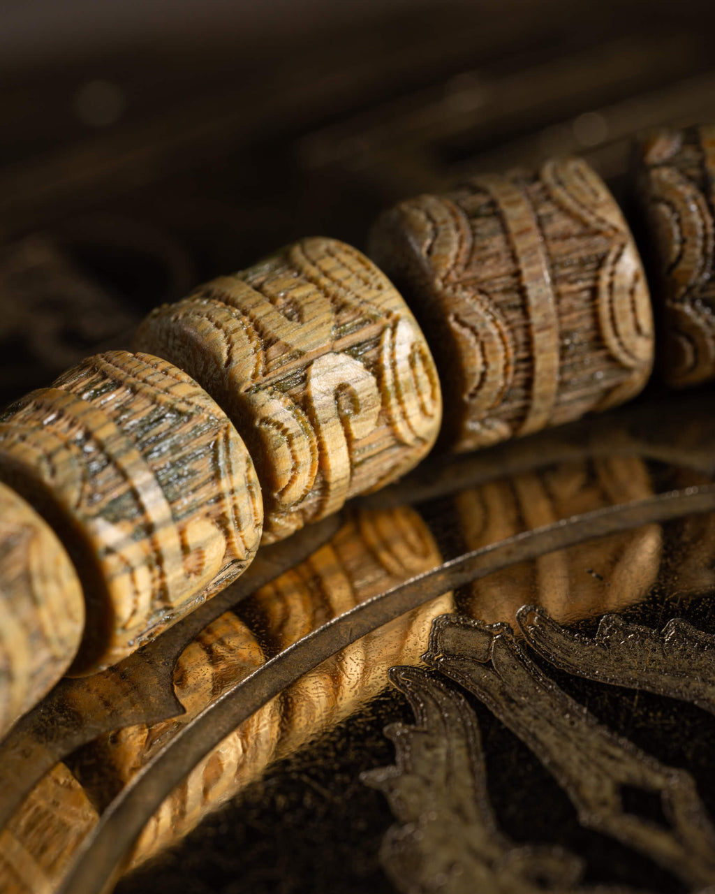 Pulsera de Madera de Sándalo en ángulo cerrado, cuentas talladas sobre superficie reflejante