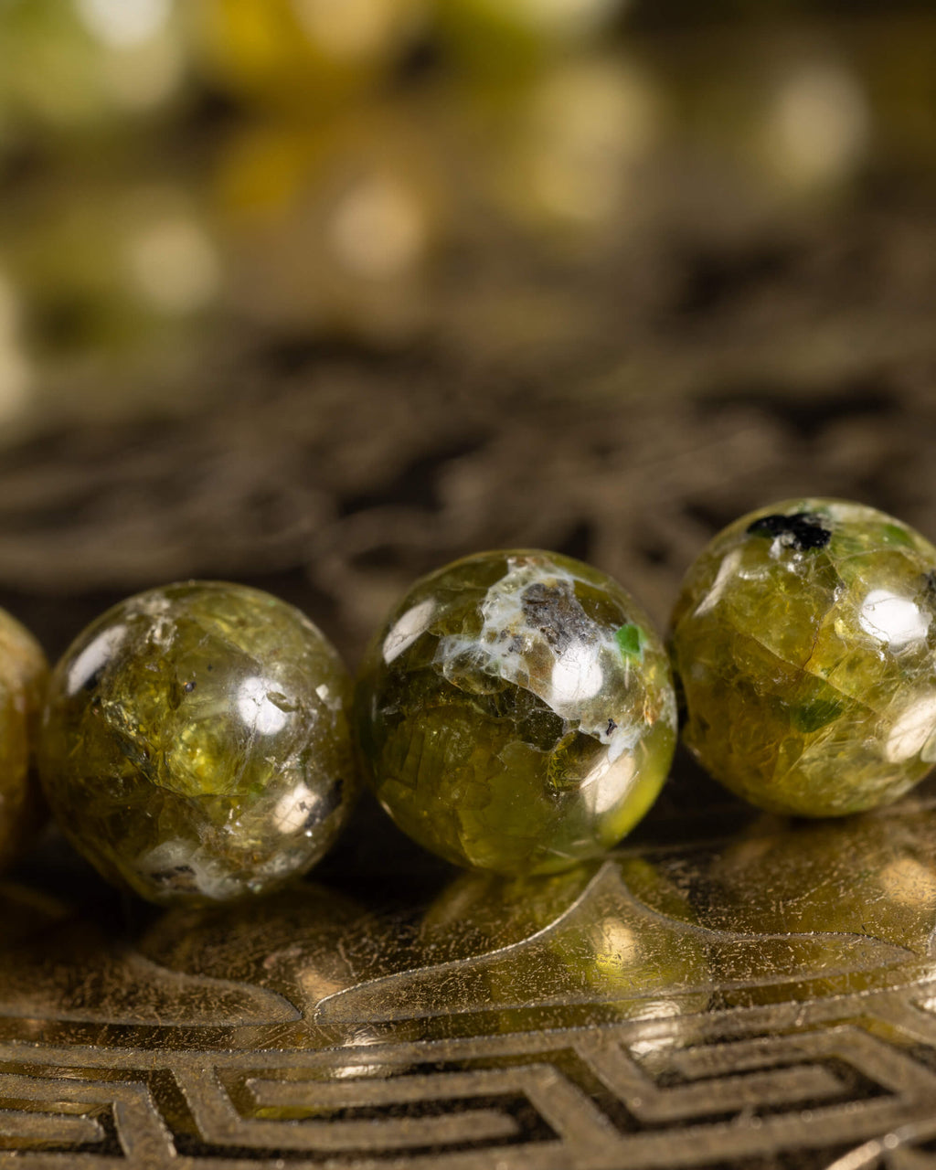 Detalle macro de las cuentas de Peridoto con reflejos de luz sobre el soporte