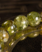 Pulsera de Peridoto en perspectiva, cuentas facetadas con reflejo sobre tabla