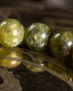 Pulsera de Peridoto en perspectiva cercana, cuentas facetadas sobre soporte grabado