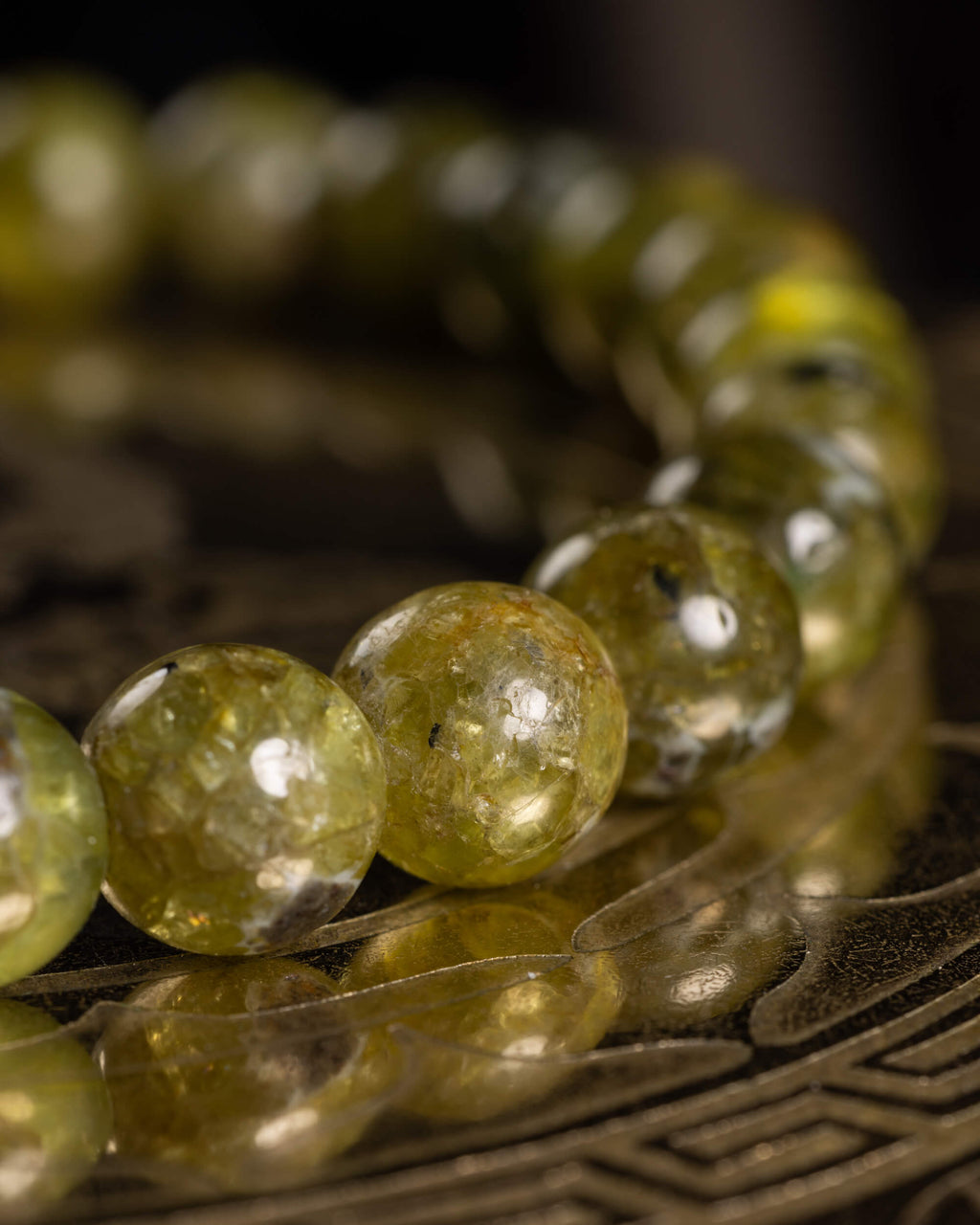 Pulsera de Peridoto vista de lado, cuentas facetadas sobre soporte grabado