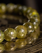 Pulsera de Peridoto vista de lado, cuentas facetadas sobre soporte grabado