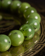 Pulsera de Jade Verde en perspectiva curva sobre placa de bronce grabada