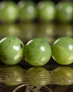 Detalle macro de las cuentas de Jade Verde reflejadas sobre bronce