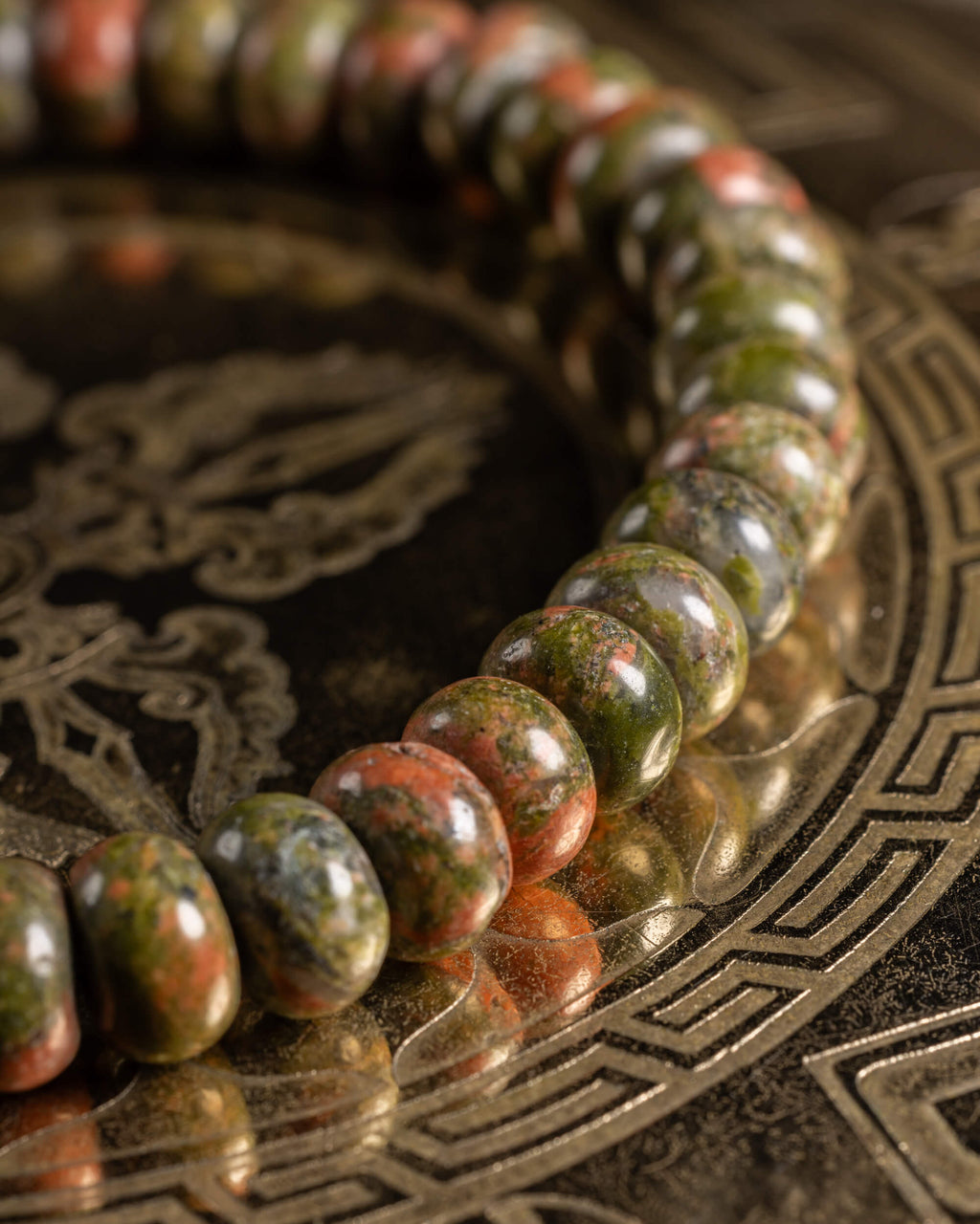 Pulsera de Jaspe Unakita en perspectiva cercana, curva de cuentas sobre soporte grabado