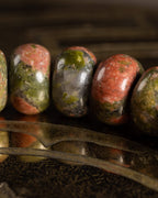 Detalle macro de cinco cuentas de Jaspe Unakita con moteado verde y rosado