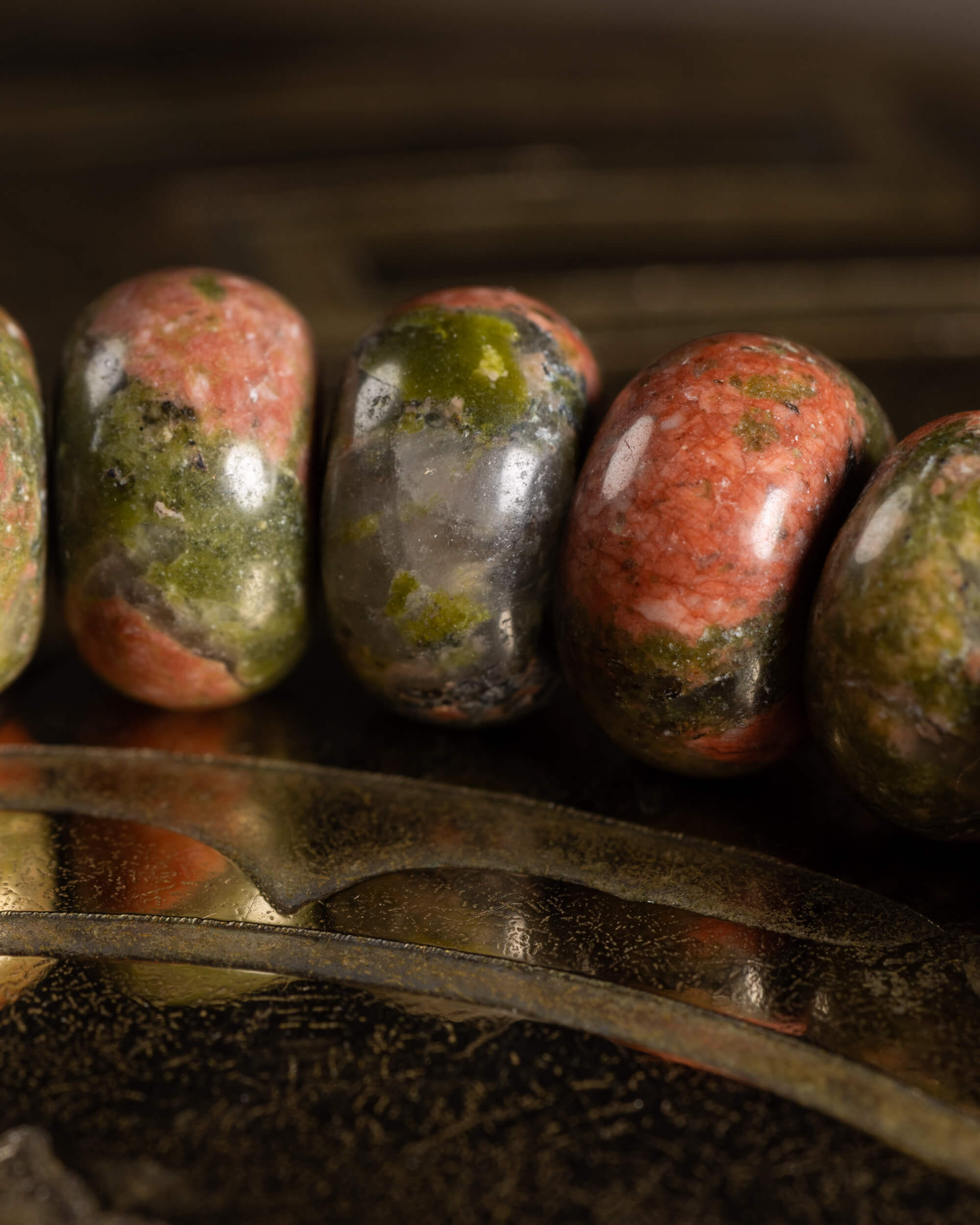 Detalle macro de cinco cuentas de Jaspe Unakita con moteado verde y rosado